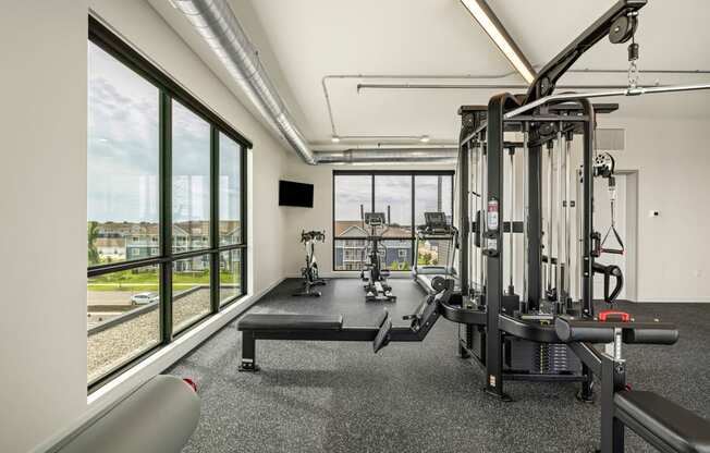 a gym with exercise equipment and windows with a view of a train at The Standard on 32nd, West Fargo, 58078