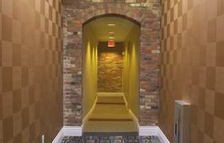 a hallway with a carpeted floor and a brick wall with a ceiling light