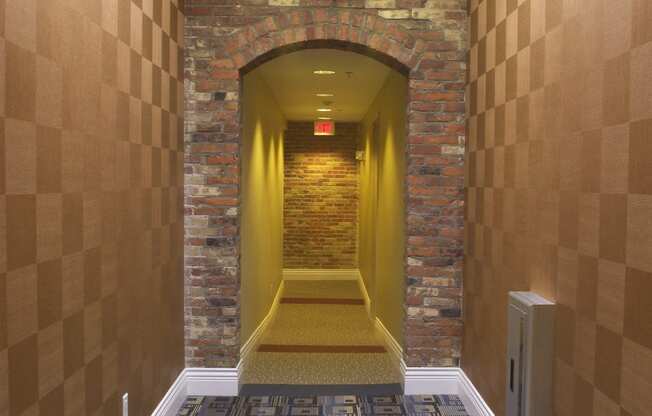 a hallway with a carpeted floor and a brick wall with a ceiling light