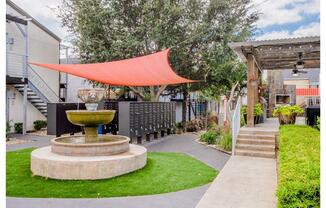 a courtyard with a red canopy and a fountain