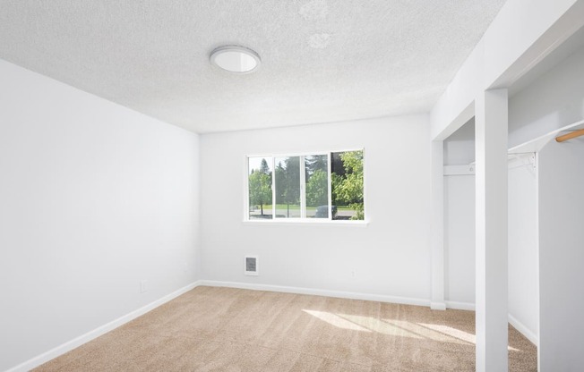 A room with a window and a wooden floor.