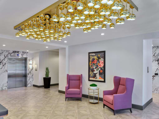 a lobby with purple chairs and a chandelier at The Encore at Ingram Manor, Maryland