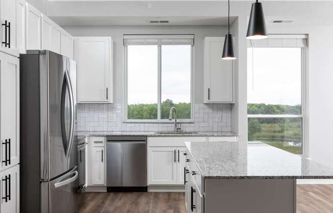 A modern kitchen with a large refrigerator and a view of the outdoors.