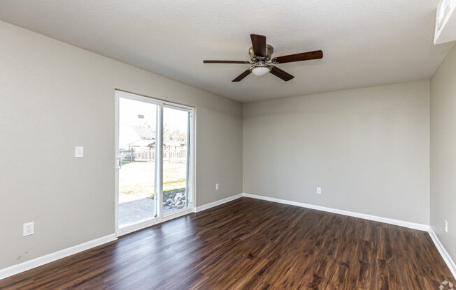 A room with a ceiling fan and sliding glass doors.