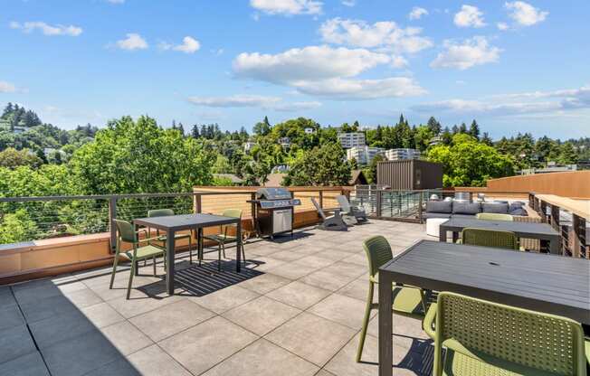 a rooftop patio with tables and chairs and a grill
