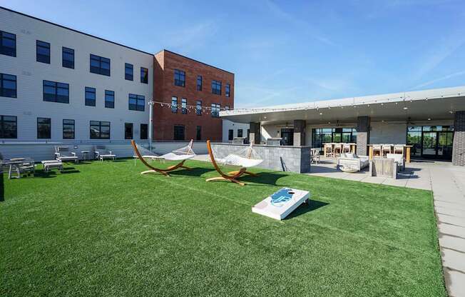 A playground with a swing set and a book on the grass in front of a building.