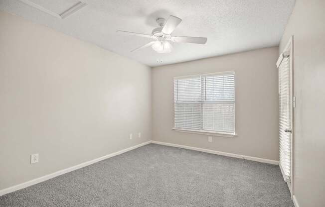 A room with a ceiling fan and a window with blinds.