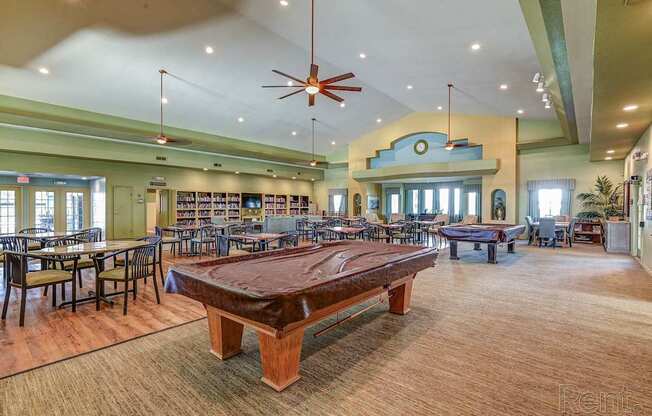 A room with a long table and chairs, a ceiling fan, and a clock on the wall.