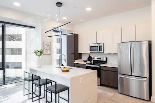 a kitchen with white cabinets and a large white island with black stools at 220 Meridian, Indianapolis, IN 46204