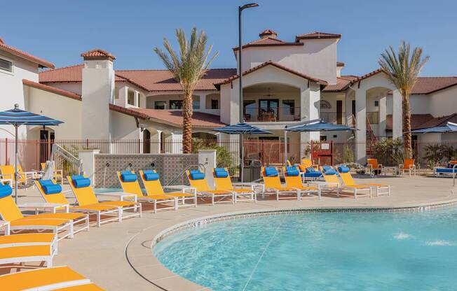 A pool with chairs and umbrellas in front of a house.