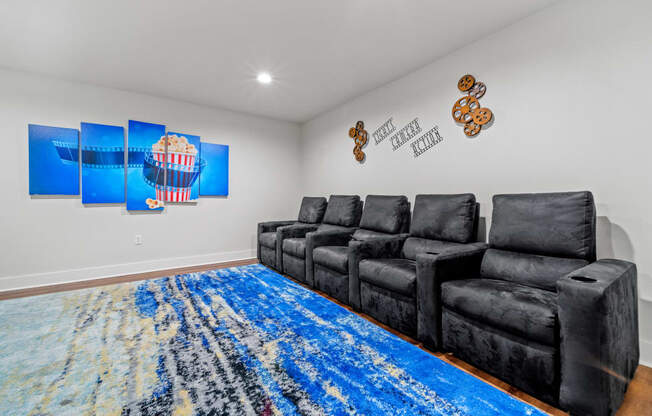 the living room has a large blue rug and black couches
