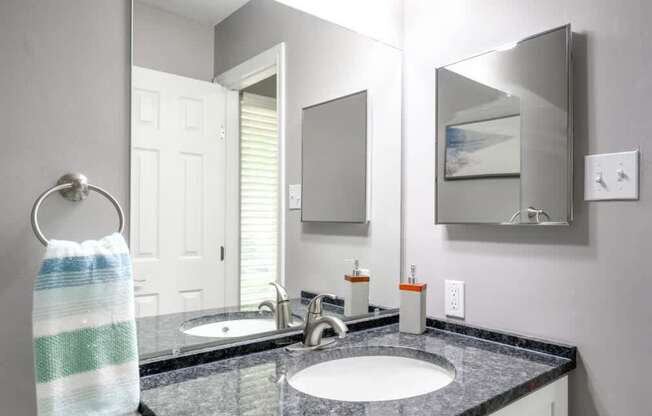 A bathroom with a black granite countertop and a white sink.
