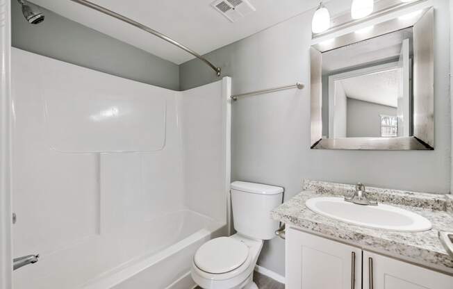 a bathroom with a toilet sink and shower and a mirror