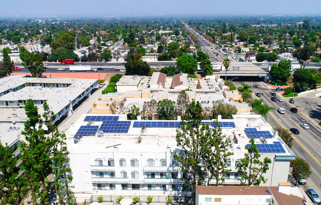 Aerial drone view of Chateau Encino showing energy-efficient white roof, solar panels, and access to 101 freeway.