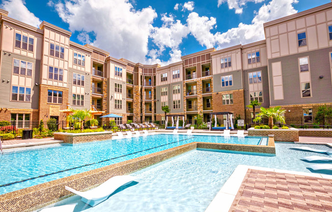 a swimming pool with lounge chairs and umbrellas in front of an apartment building at Artesia Big Creek, Alpharetta, GA, 30005