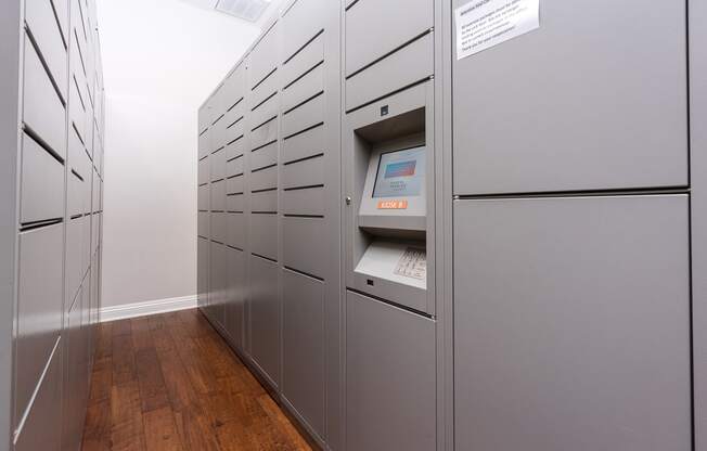 a row of gray lockers in a room with hardwood floors and a white wall