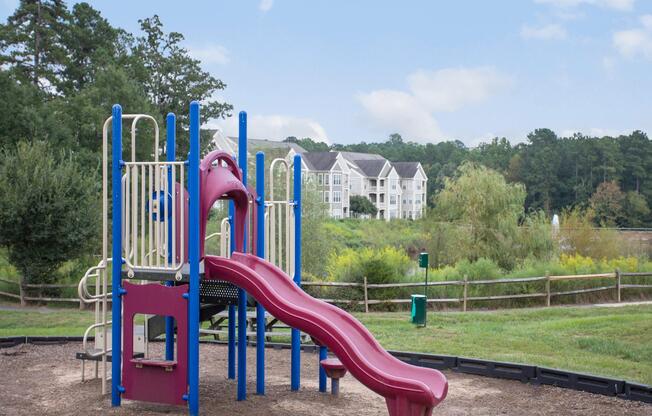 Outdoor playground surrounded by green grass at family-friendly apartments in Durham, North Carolina