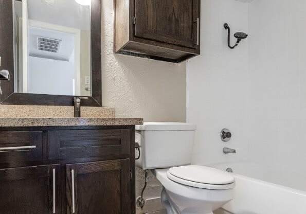 A white toilet sits in a bathroom with a wooden cabinet and a mirror above it.