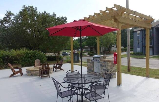 a patio with a table and chairs under a red umbrella