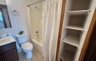 A white bathroom with a toilet, sink, and shower.
