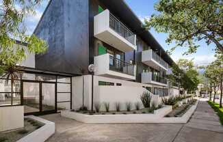 A modern building with a white and black exterior and a landscaped front yard.