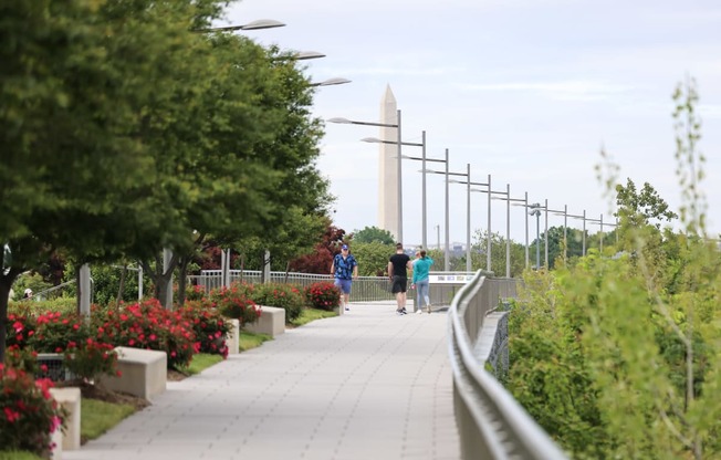 a group of people walking down a pathway with a monument in the background