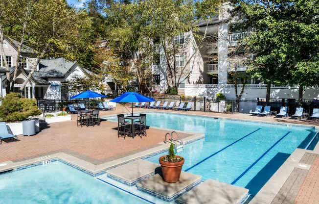 A pool area with a blue umbrella and chairs.