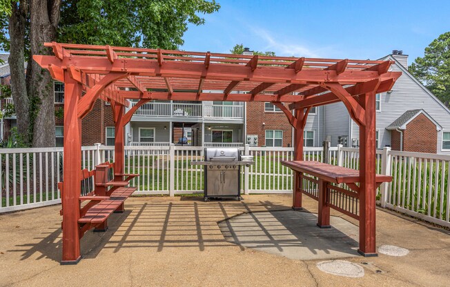 A red pergola with benches is in the foreground of a residential area.
