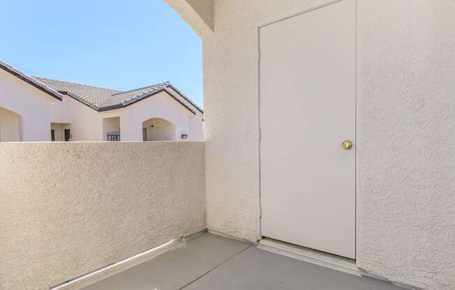 the patio of a house with a white door and a balcony