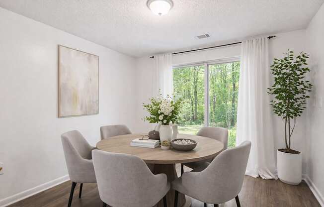 A dining room with a round table and grey chairs.