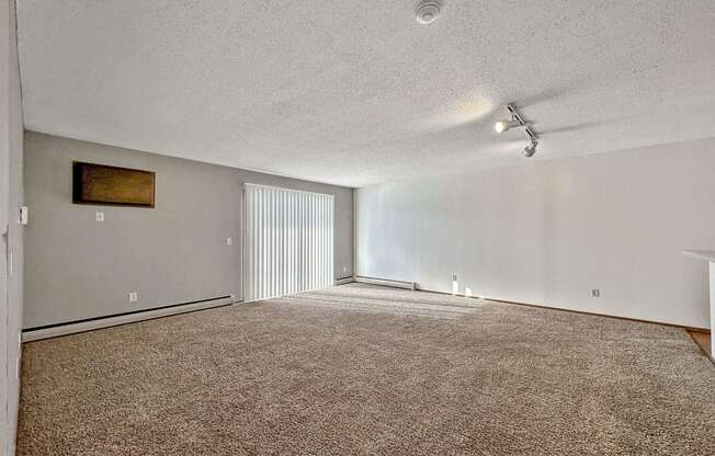 an empty living room with carpet and a ceiling fan