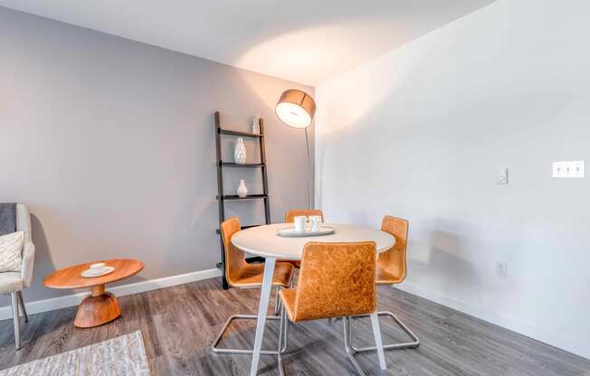 a dining area with a round table and orange chairs