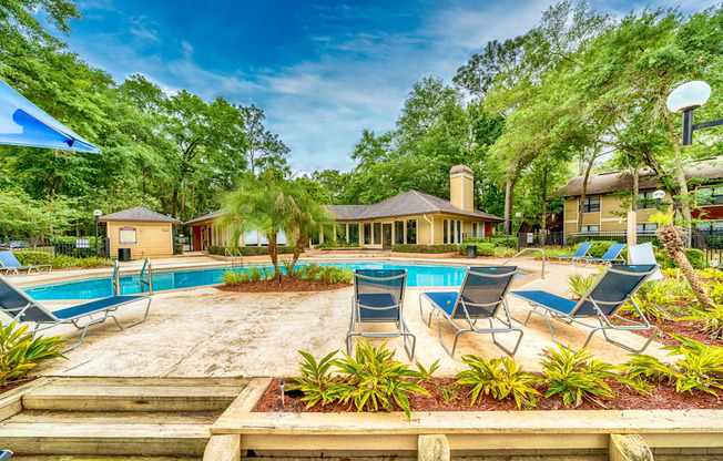 a swimming pool with chaise lounge chairs and trees in the background at Northlake Apartments, Jacksonville, 32218