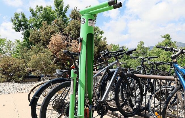 A green bike rack with bikes parked on it.