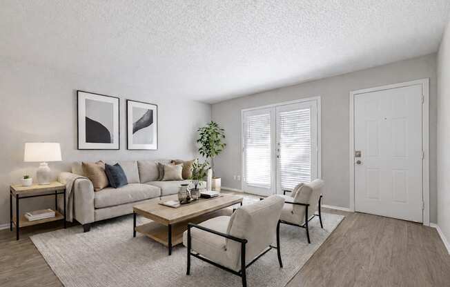 A living room with a grey couch, a coffee table, and two chairs.