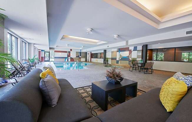 An indoor pool with a sofa, a table, and beach chairs.