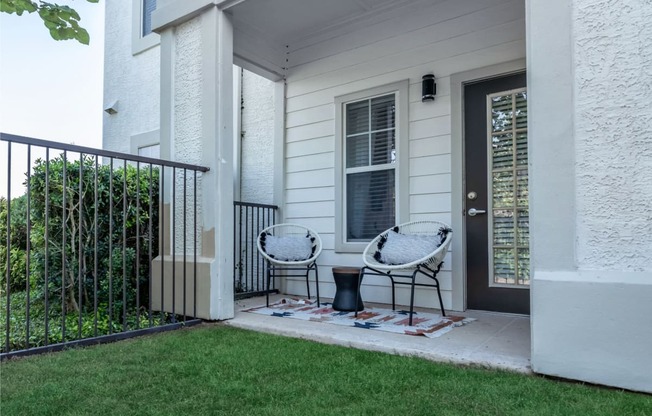 two chairs on a patio in front of a house