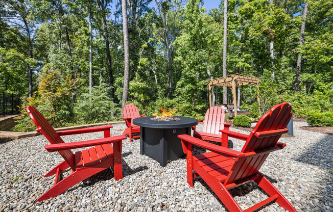 a group of red chairs sitting around a firepit