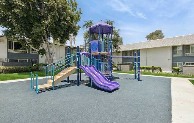 A playground with a purple slide and a wooden ramp.