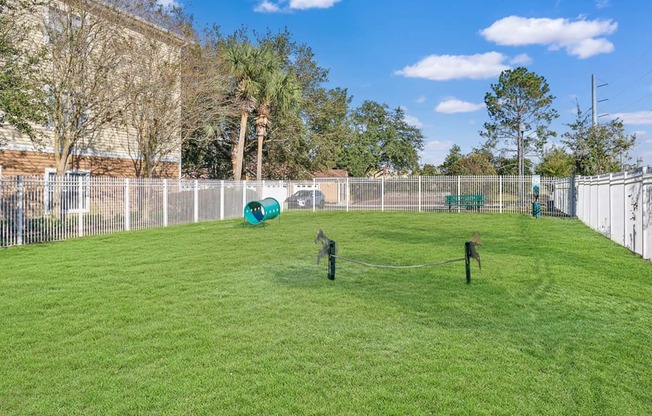 a fenced in backyard with a large yard and a dog cage