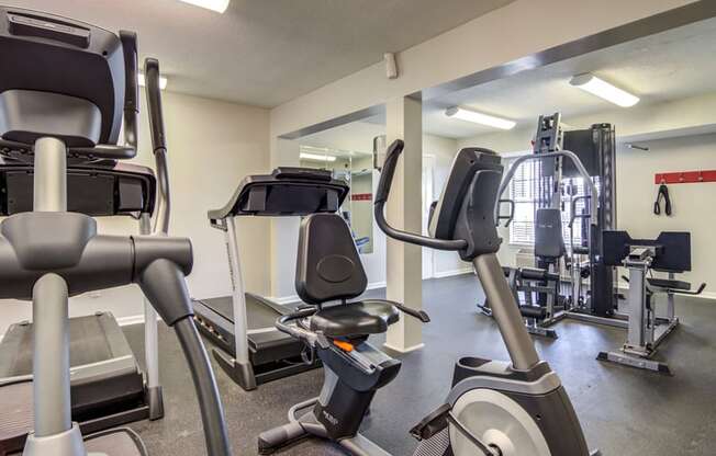 Gym area with view of a variety of weight machines and training equipment with wooden panel ceilings and gray carpet