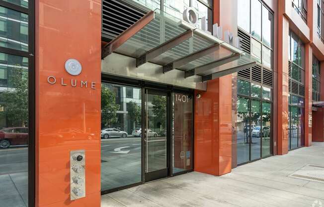 The entrance to a building with a glass door and a sign that reads "OLUME".