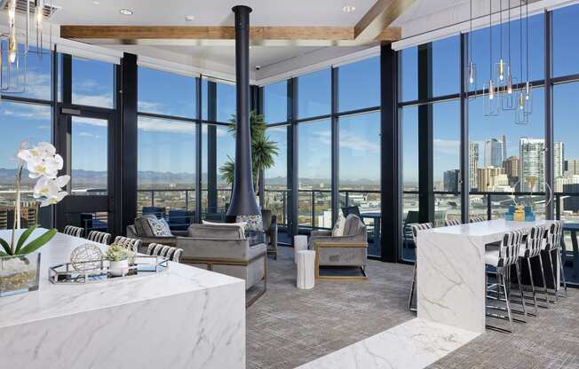 Sky lounge with fireplace connected to the ceiling, surrounding seating and large windows with view of Denver skyline