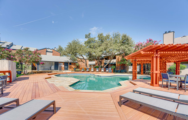 a swimming pool with a wooden deck with tables and chairs