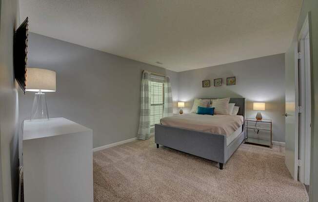 A bedroom with a bed, nightstand, and lamp.