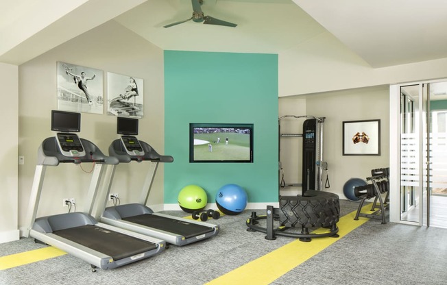 a home gym with a green accent wall and a yellow stripe on the floor