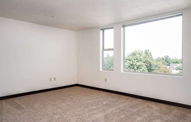 an empty room with two windows and a carpeted floor
