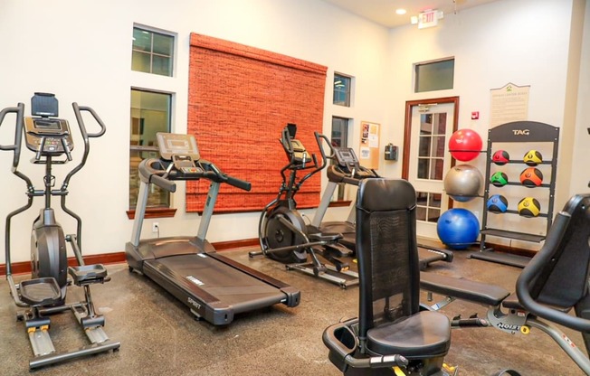 a gym with cardio equipment and weights at the at the village apartments