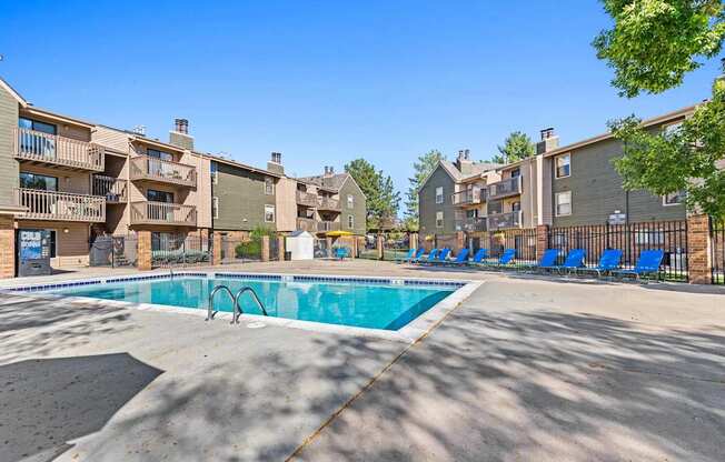 A swimming pool surrounded by apartment buildings on a sunny day.