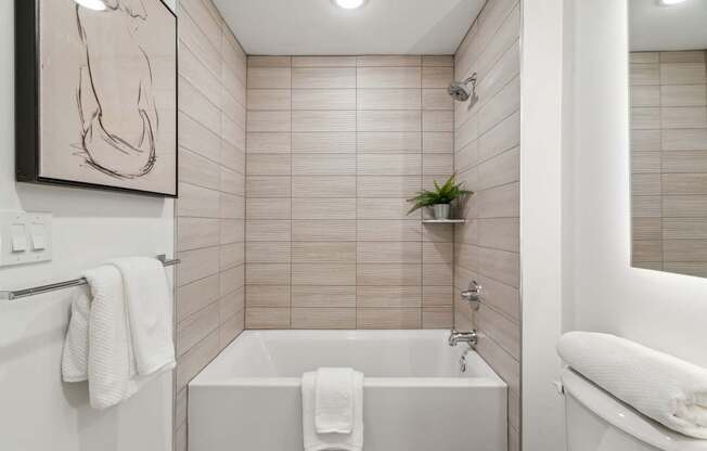 A white bathroom with a tub and a towel hanging on the side.